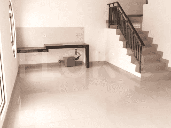 Dapur kecil yang ringkas dengan kompor gas, meja, dan tangga menuju ke lantai atas.