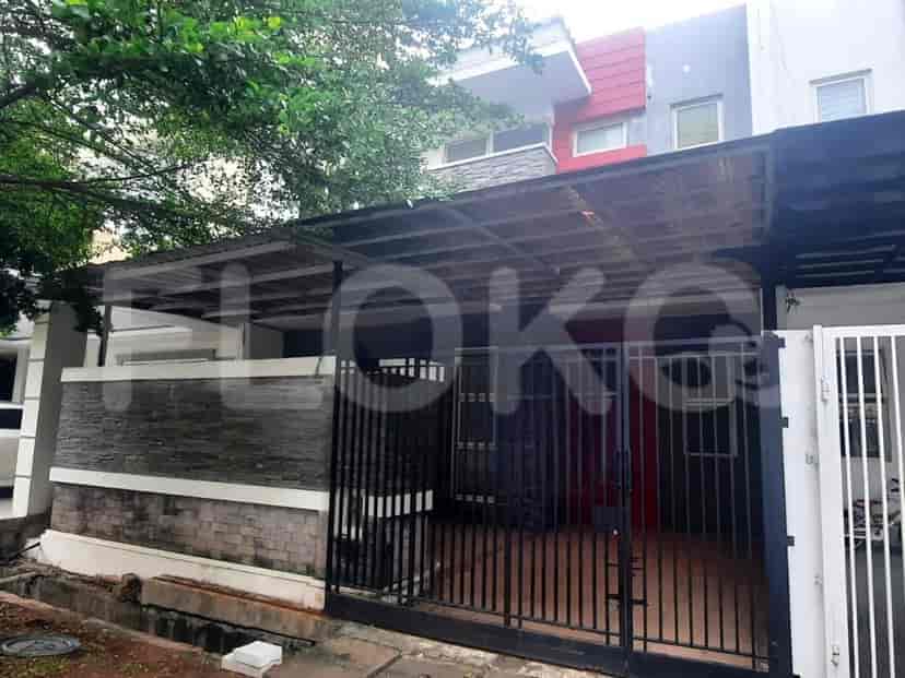 Sebuah rumah dua lantai dengan carport, gerbang logam hitam, dan dinding bata.