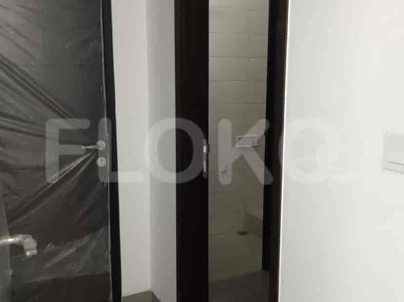 Pemandangan ke kamar mandi dengan pintu terbuka, pintu utama terlihat di sudut.