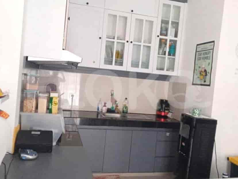 A modern kitchen with granite countertops, overhead cabinets, and a refrigerator.