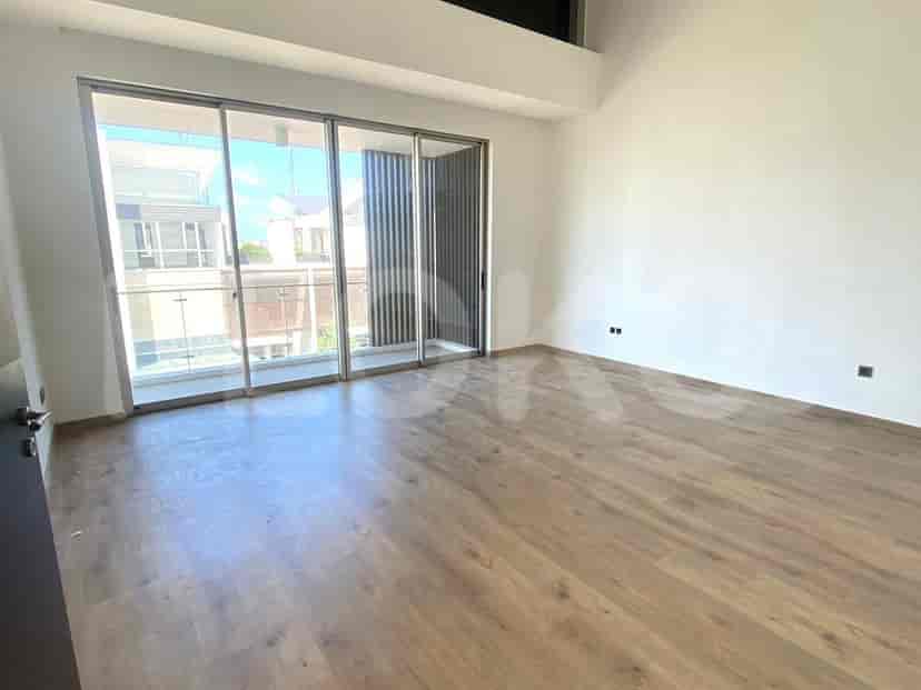 Kamar tidur dengan lantai kayu, pintu kaca geser besar yang mengarah ke balkon, dan desain minimalis modern.