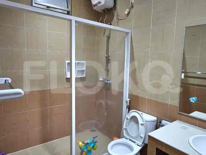Kamar mandi modern dengan pancuran berkaca, toilet, dan dinding berubin.