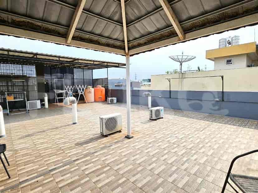 Teras atap yang luas dengan lantai berubin, unit pendingin ruangan, dan area tempat duduk tertutup.