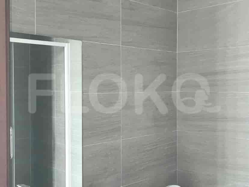Kamar mandi dengan dinding ubin abu-abu, pancuran, dan toilet.