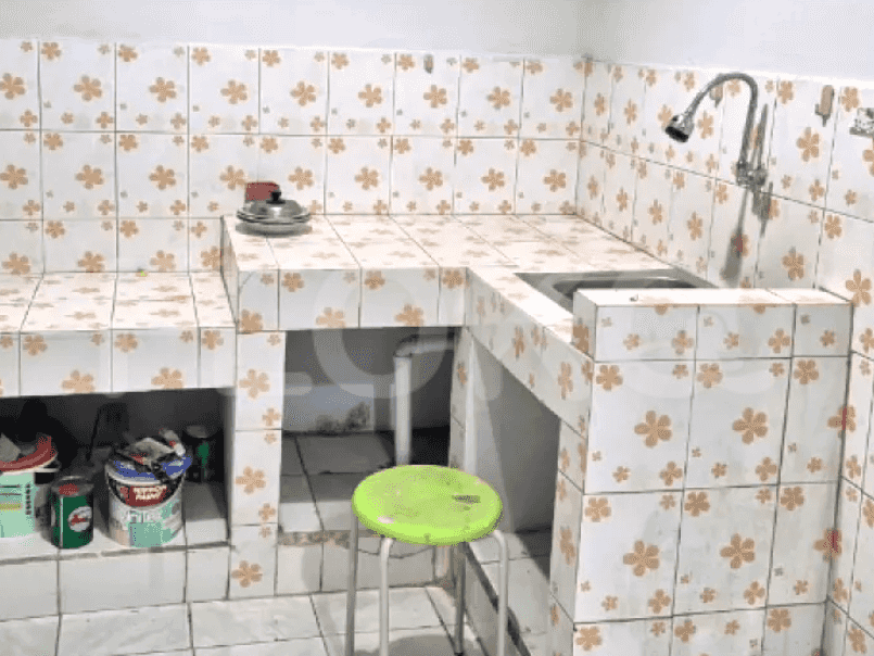 A kitchen with floral tiled walls, a sink, and a counter.