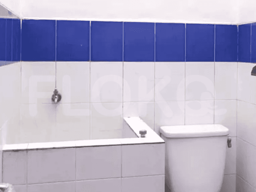 Kamar mandi dengan dinding ubin putih dan biru, toilet, dan shower.