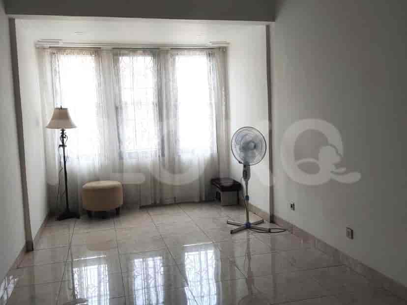 An empty room with a window, a floor fan, and a standing lamp.
