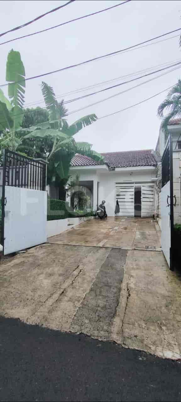 A two-story white house with a gated entrance, driveway, and lush greenery.