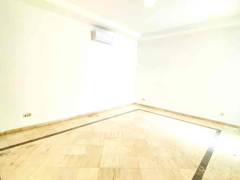 An empty room with a marble floor, white walls, and an air conditioning unit.