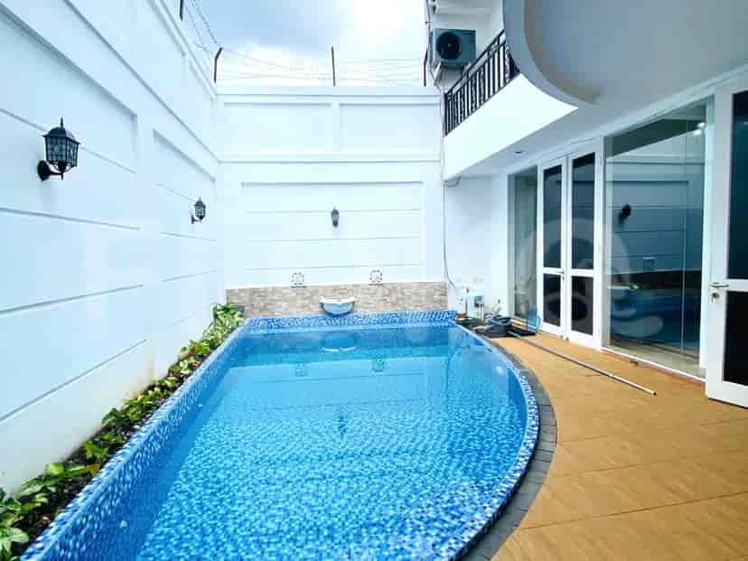 A view of a swimming pool surrounded by a white wall with a black fence.