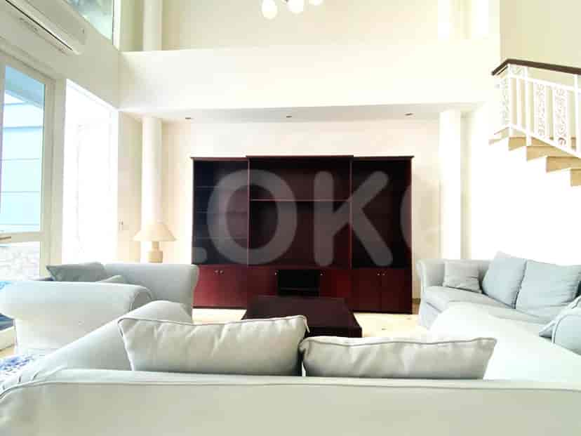 A large living room with sofas, an entertainment unit, and a staircase.