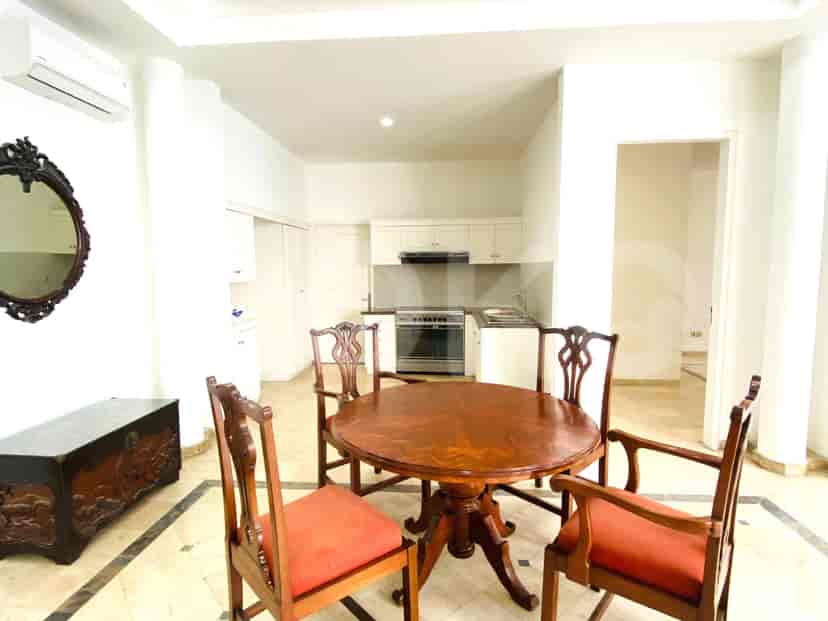 A dining area with a wooden table and chairs and a kitchen.