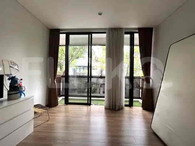 Kamar tidur dengan pintu kaca geser besar yang mengarah ke balkon atau area luar ruangan dengan pemandangan tanaman hijau subur.