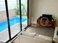Ruang tamu dengan pemandangan kolam renang dan sofa putih.