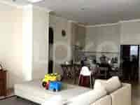 Area ruang tamu dan ruang makan yang digabungkan dengan sofa putih dan meja makan dengan kursi.