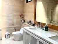 Kamar mandi yang terang dengan wastafel ganda, toilet, dan desain modern.