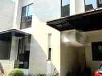 Rumah modern dengan carport dan jendela besar.