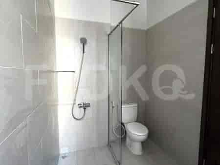 Kamar mandi dengan shower walk-in, toilet putih, dan dinding berubin.