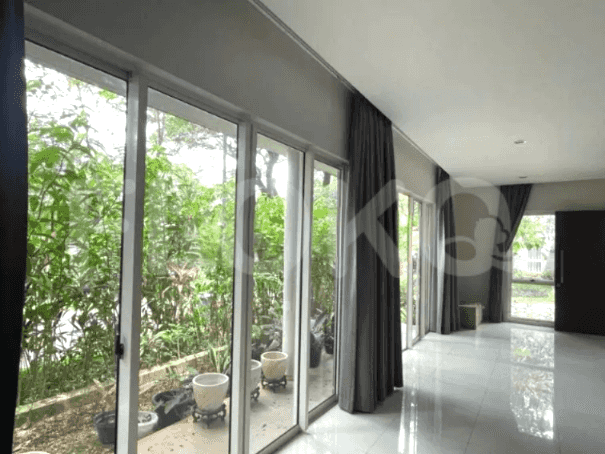A spacious living room with large windows and a view of a lush garden.
