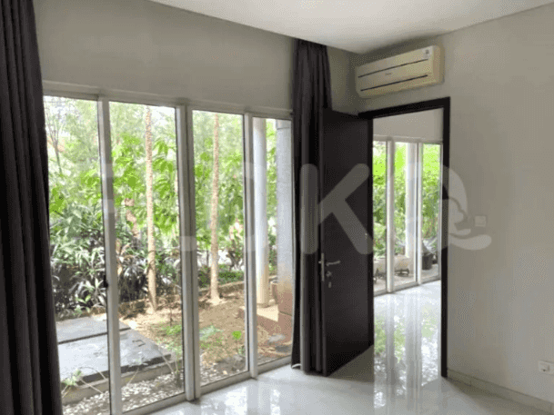 A room with large windows, sheer curtains, and a view of the garden.