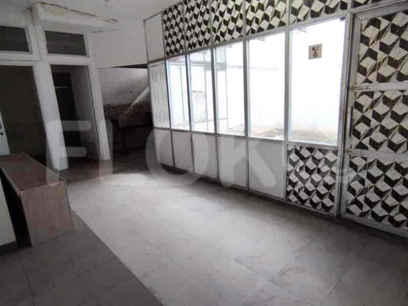 Area ruang tamu terbuka dengan jendela besar, lantai ubin, dan perlengkapan modern.