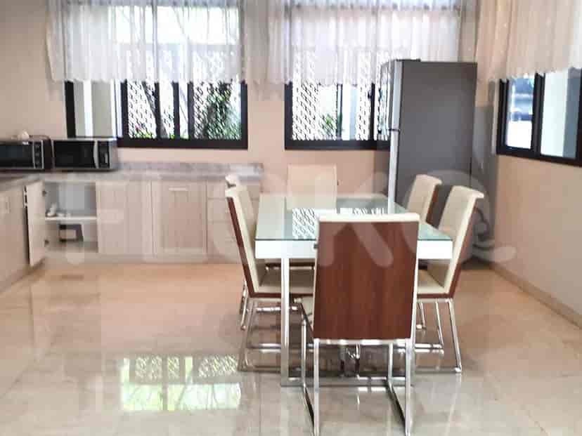 A modern kitchen with a dining area, featuring white cabinets and granite countertops.