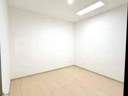 An empty room with light wooden flooring and white walls.