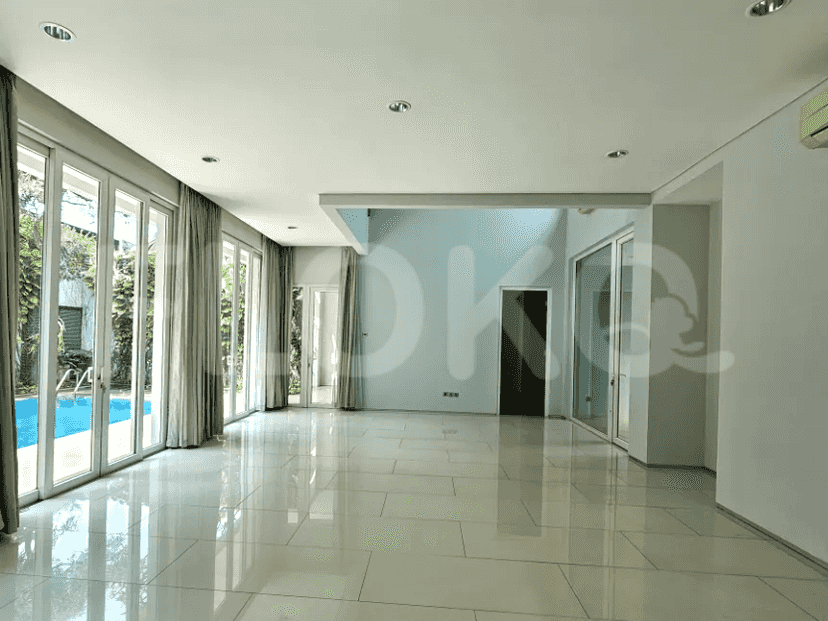 A bright living room with high ceilings, glass doors, and a view of the swimming pool.