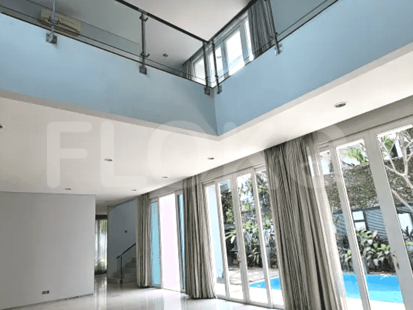 A living room with an upper-level view, featuring glass railings, and natural light.