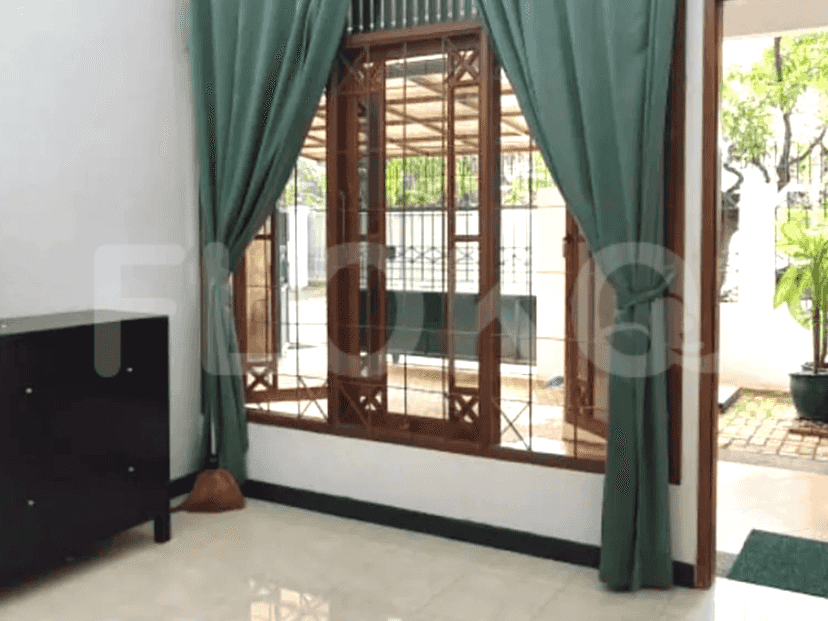 A living room with green curtains, wooden windows, a black cabinet, and a sofa.