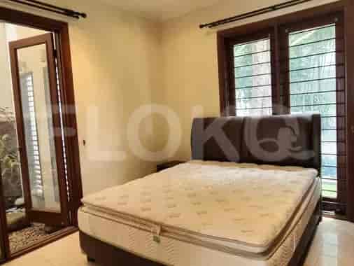 A bedroom with a bed, a large window, and a garden.