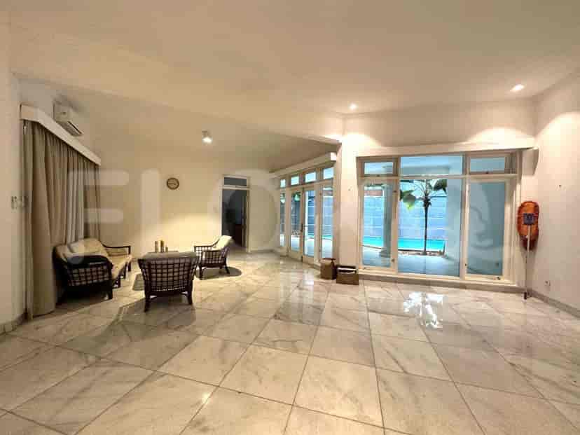 A spacious living room with marble flooring, seating area, and access to a swimming pool.