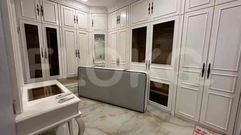 Walk-in closet with custom built-in wardrobes, a vanity, and an ottoman.