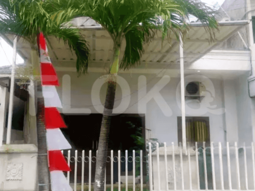 A two-story house with a white facade, palm trees, and a white fence.