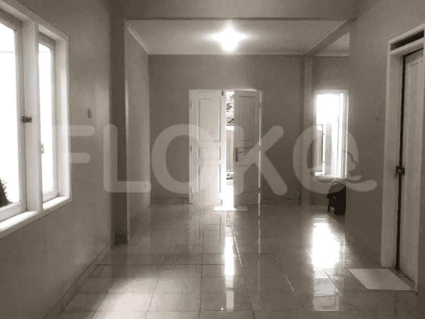 An empty living room with tiled floors, two windows, and a door leading outside.