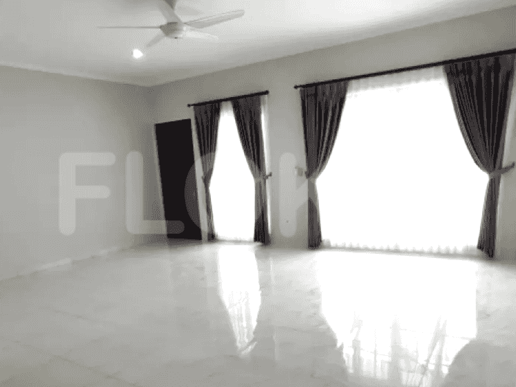 A spacious, empty living room with large windows and a ceiling fan, indicating a modern design.