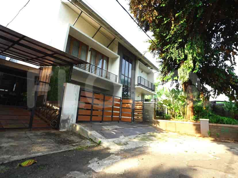 A modern two-story house with a large gate, trees, and a carport.