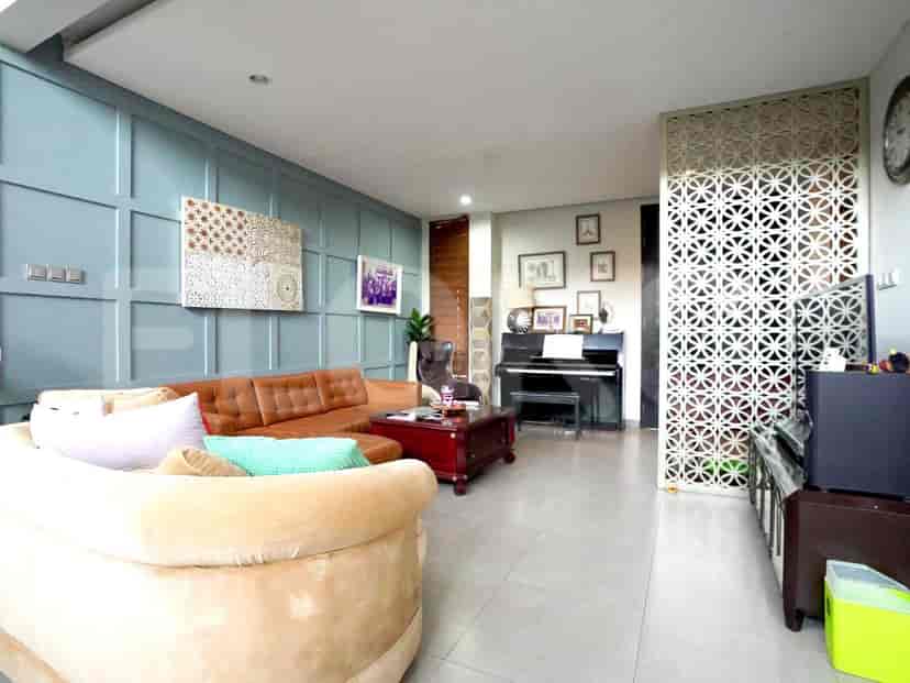 A living room with blue paneled wall, a brown leather sofa, and a piano.