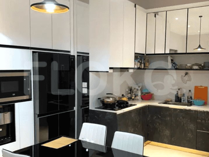 Dapur modern dengan lemari putih, meja hitam, dan lemari es stainless steel.
