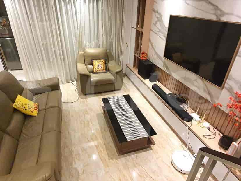 Ruang tamu dengan sofa, kursi berlengan, meja kopi, dan TV yang dipasang di dinding.