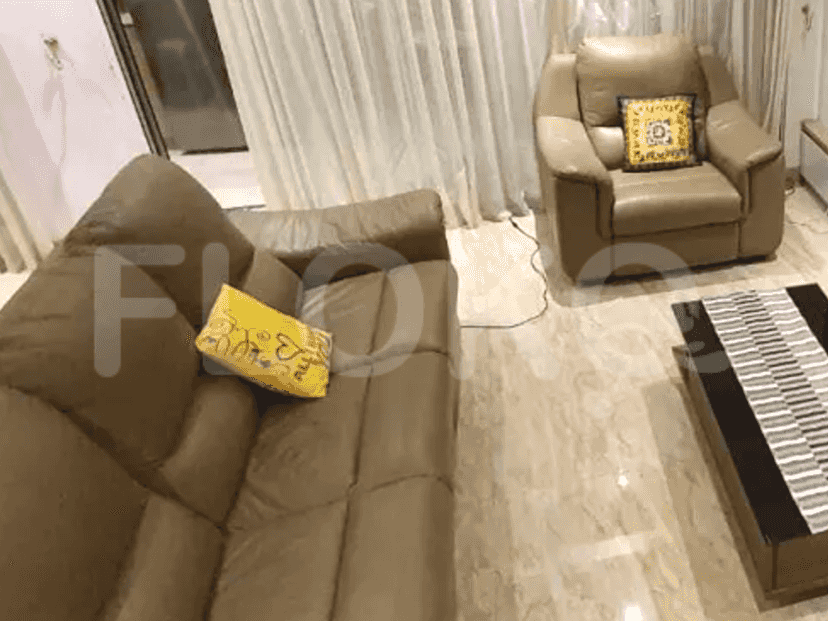 Ruang tamu dengan sofa cokelat dan kursi, menampilkan meja kopi.