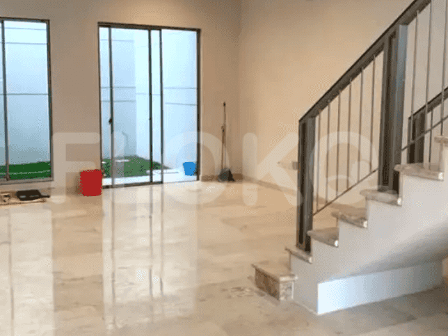 An empty living room with marble flooring, a staircase, and sliding glass doors leading to a small garden.