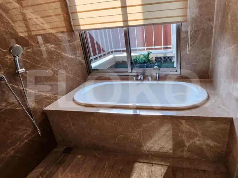A bathroom with a bathtub, a window, and marble walls.