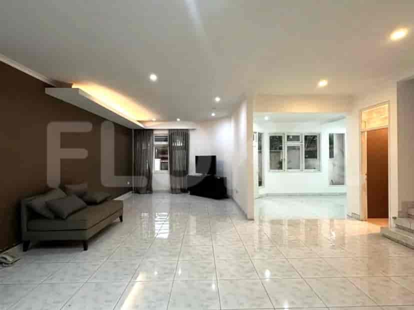 A spacious living room with a sofa, TV, and open access to another room.