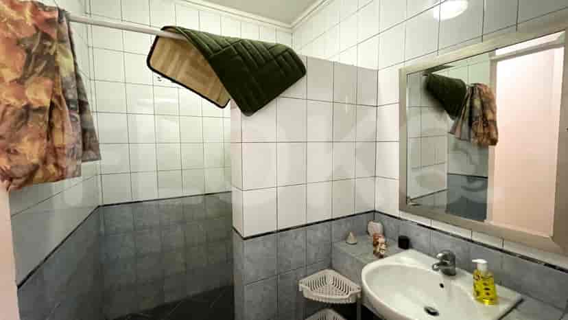 A bathroom with a sink, a mirror, and a shower area.