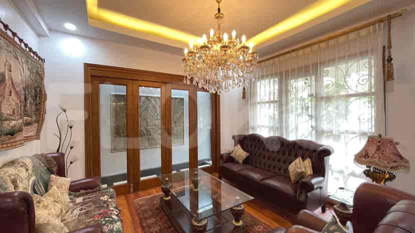An elegant living room featuring a crystal chandelier, leather sofa, and a glass coffee table.