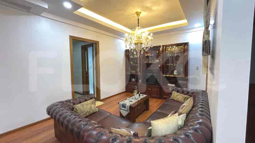 A cozy living room setup featuring a curved leather sofa, TV cabinet, and chandelier.