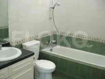 A bathroom with a bathtub, toilet, and vanity unit, featuring green tiles.