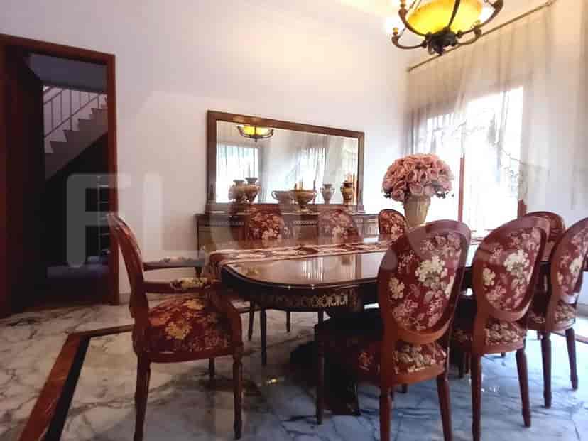 A dining room with a large wooden dining table and matching chairs, set against a backdrop of marble flooring and white walls.