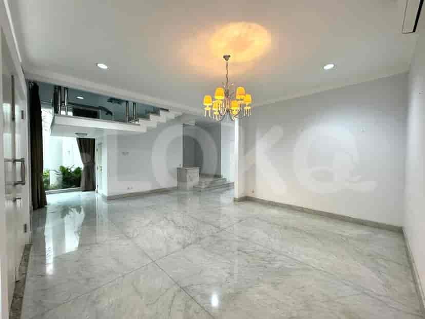 A well-lit living area featuring a staircase leading to the upper floor, marble flooring, and a chandelier.